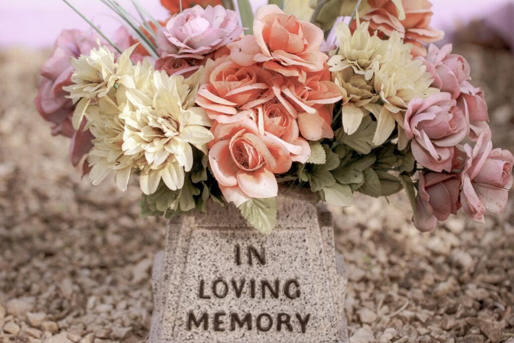 flowers on a stone that says in loving memory
